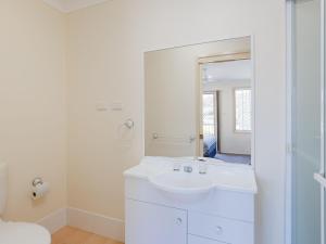 La salle de bains blanche est pourvue d'un lavabo et d'un miroir. dans l'établissement Clancys, à Corlette