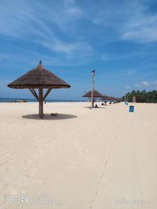 a beach with two straw umbrellas on the sand at His Grace BEACH Cottages - Private Beach at MALPE in Udupi