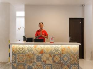 a man standing behind a counter in a room at Super OYO Collection O 90023 Damar Kusumo Guest House in Yogyakarta