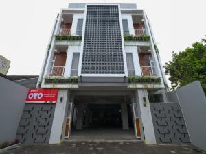 een hoog wit gebouw met een parkeergarage bij Super OYO Collection O 90023 Damar Kusumo Guest House in Yogyakarta