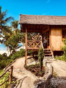 a small hut on a beach with palm trees at BaraCoco Bungalows in Bira