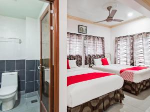 two beds in a room with a toilet and a sink at Super OYO 258 Hotel SMC Alam Avenue in Shah Alam