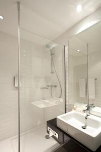 ein weißes Bad mit einem Waschbecken und einer Dusche in der Unterkunft Holiday Inn Lille Ouest Englos, an IHG Hotel in Englos