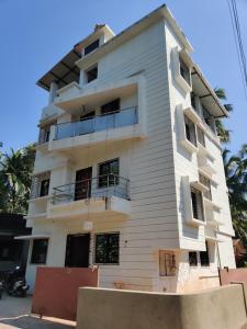 a white building with balconies on a street at Bandekar Home Stay in Malvan