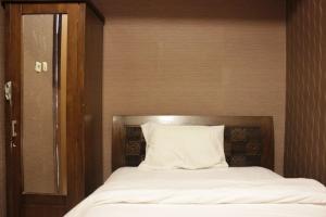 a bed with a silver headboard and a white pillow at Chic and Cozy 2BR Apartment at Pinewood Jatinangor near JATOS By Travelio in Cilimus 2