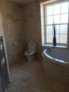 a bathroom with a tub and a toilet and a window at Ellison Hall in Hebburn-on-Tyne