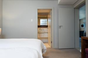 a bedroom with a white bed and a bathroom at Zimbali Suite 214 in Ballito