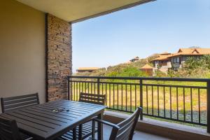 a wooden table and chairs on a balcony with a view at Zimbali Suite 214 in Ballito