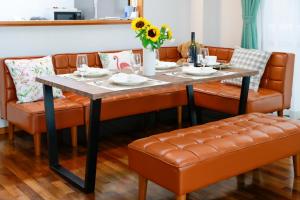 a dining room table with orange leather chairs and a table with at Sunset Beach Vacation House in Chatan