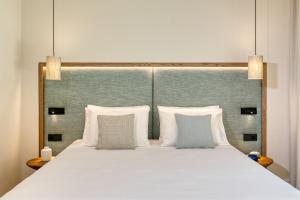 a large white bed with two pillows and a headboard at Vathi Cove Luxury Resort & Spa in Chrysi Ammoudia