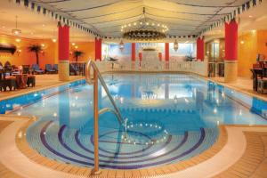 a large swimming pool in a hotel with a restaurant at SEETELHOTEL Villa Esplanade mit Aurora in Heringsdorf