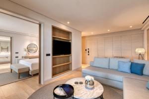 a living room with a blue couch and a bedroom at Vathi Cove Luxury Resort & Spa in Chrysi Ammoudia