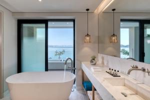 a bathroom with a tub and a large mirror at Vathi Cove Luxury Resort & Spa in Chrysi Ammoudia