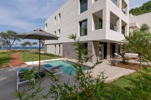 a house with a swimming pool and an umbrella at Vathi Cove Luxury Resort & Spa in Chrysi Ammoudia