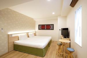 a bedroom with a bed and a tv and a table at karaksa hotel Sapporo in Sapporo