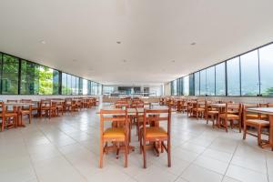 a dining room with tables and chairs and windows at OYO Residencial Muriqui Apart Hotel, Mangaratiba in Vila Muriqui