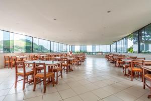 - une salle à manger avec des tables, des chaises et des fenêtres dans l'établissement OYO Residencial Muriqui Apart Hotel, Mangaratiba, à Vila Muriqui