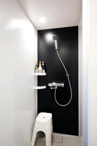 a bathroom with a shower in a black wall at karaksa hotel Sapporo in Sapporo