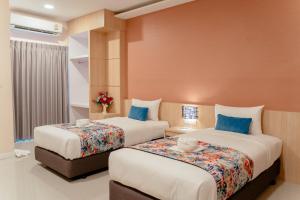 two beds in a hotel room with blue pillows at It's me Keawanong Hotel in Nakhon Ratchasima