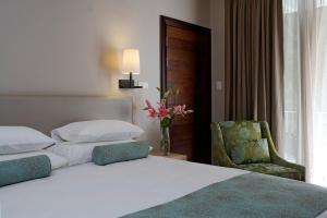 een slaapkamer met een bed, een stoel en een raam bij Chapmans Peak Beach Hotel in Hout Baai
