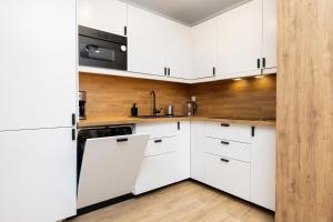 a white kitchen with white cabinets and a sink at Apartamenty PLATANY z Parkingiem by Renters in Kołobrzeg