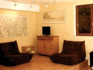 a living room with two chairs and a television at Les Barelles in Saint-Jean-de-Thurigneux