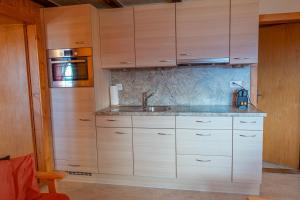 a kitchen with wooden cabinets and a sink at Chalet Allegra in Rosswald