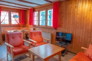 a living room with red chairs and a television at Chalet Allegra in Rosswald