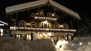una casa cubierta de nieve por la noche con luces de Navidad en Landhaus Lenzenhof, en Reit im Winkl