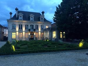a large house with lights on the front of it at La Maison Dans le Parc in Saint-Dizier