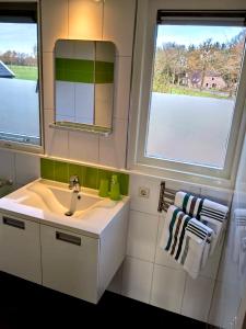 a bathroom with a sink and a mirror and two windows at Appartement Soerte Es in Wapse