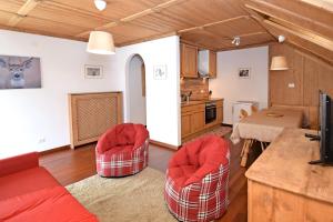 ein Wohnzimmer mit 2 roten Stühlen und eine Küche in der Unterkunft Aurturist S Candido Roulette in Innichen