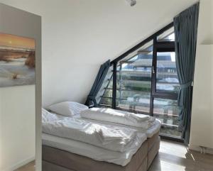 Cama en habitación con ventana grande en Zonnestralen Egmond en Egmond aan den Hoef