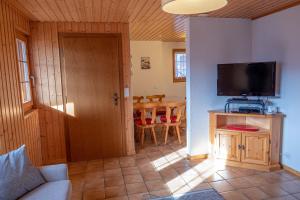 a living room with a television and a table at Chalet Gerbera in Rosswald