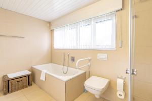 a bathroom with a tub and a toilet and a window at Haus Alpsee in Immenstadt im Allgäu +7 photos
