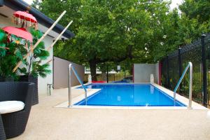 a swimming pool in a yard next to a fence at Beechworth On Bridge Motel in Beechworth