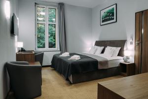 um quarto de hotel com uma cama e uma cadeira em Hotel Grey Spa em Szklarska Poręba