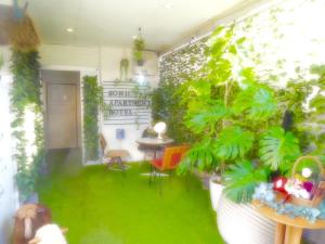 ein Zimmer mit grünen Pflanzen, einem Tisch und Stühlen in der Unterkunft SONIC APARTMENT HOTEL in Dazaifu