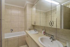 a bathroom with two sinks and a mirror and a tub at Laguna Grove 10 in Knysna