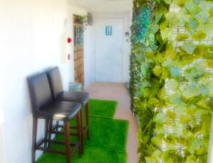 um quarto com uma cadeira e uma parede verde em SONIC APARTMENT HOTEL em Dazaifu