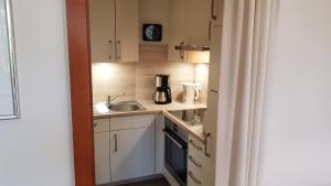 a small kitchen with white cabinets and a sink at Kurpark Appartement in Glücksburg