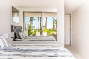 1 dormitorio con 2 camas y ventana grande en The Edge Front Line Beach Luxury and Spa en Estepona