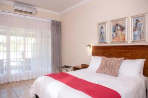 a bedroom with a large white bed with a red blanket at Palm Park Hotel in Ellisras