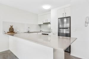 a kitchen with white cabinets and a refrigerator at Beachcomber on the Spit in Mooloolaba