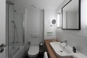 ein Badezimmer mit einem Waschbecken, einem WC und einem Spiegel in der Unterkunft Holiday Inn Berlin City-West, an IHG Hotel in Berlin