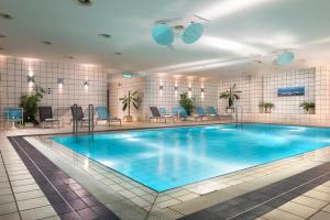 una gran piscina en un hotel con sillas y mesas en Holiday Inn Berlin City-West, an IHG Hotel, en Berlín