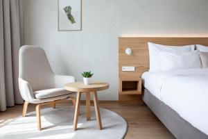 a bedroom with a bed, chair, table and lamp at Botanique Hotel Prague in Prague