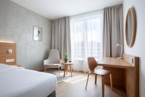 a hotel room with a bed and a desk and a window at Botanique Hotel Prague in Prague