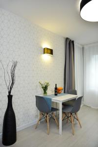 a dining room with a table and chairs and a vase at Apartamenty TOP Garbary in Poznań