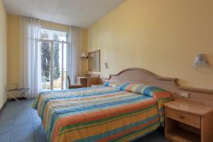 una camera da letto con un letto, un tavolo e una finestra di Hotel Marco Polo a Garda Altre 33 foto